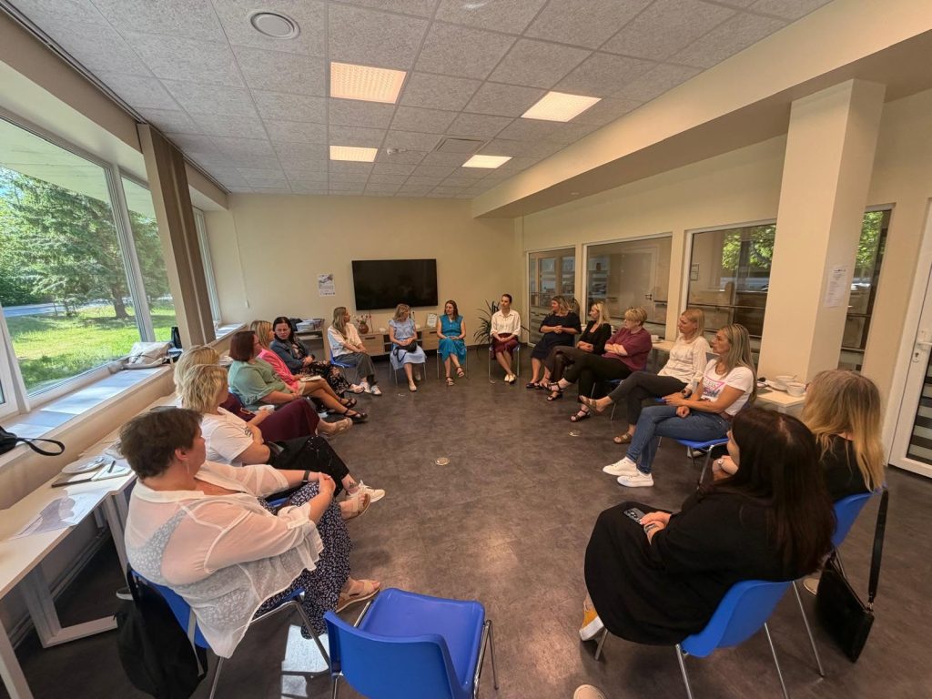 Group of women participating in a discussion or workshop in a bright, modern meeting room with large windows and comfortable seating. Group of women participating in a discussion or workshop in a bright, modern meeting room with large windows and comfortable seating.