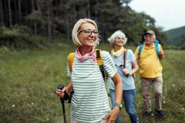 Group of senior hikers enjoying a nature walk in a lush green field, showcasing active outdoor lifestyle and companionship. Group of senior hikers enjoying a nature walk in a lush green field, showcasing active outdoor lifestyle and companionship.