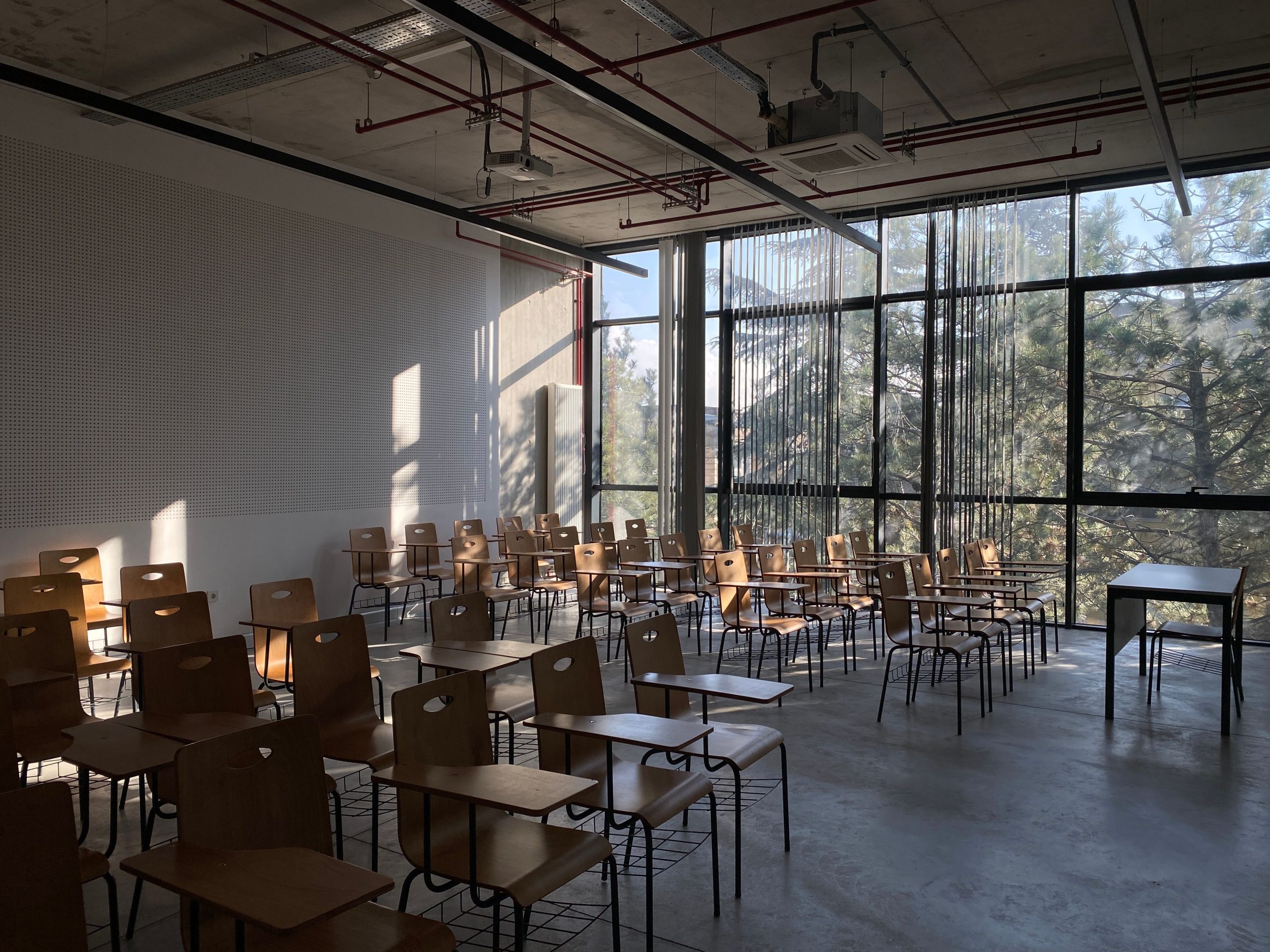 Modern classroom with wooden desks and chairs, large windows allowing natural light, and a minimalist design. Ideal for educational settings and learning environments. Modern classroom with wooden desks and chairs, large windows allowing natural light, and a minimalist design. Ideal for educational settings and learning environments.