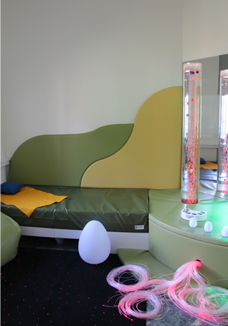 A calming sensory room designed for psychosocial and physical rehabilitation, featuring soft green seating, colorful LED bubble tubes, and tactile elements to support stress relief and social inclusion for vulnerable individuals. A calming sensory room designed for psychosocial and physical rehabilitation, featuring soft green seating, colorful LED bubble tubes, and tactile elements to support stress relief and social inclusion for vulnerable individuals.