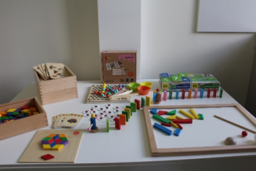 Colorful educational toys and rehabilitation materials displayed on a table, including building blocks, puzzles, and sorting games, designed to support psychosocial and physical rehabilitation for vulnerable individuals. Colorful educational toys and rehabilitation materials displayed on a table, including building blocks, puzzles, and sorting games, designed to support psychosocial and physical rehabilitation for vulnerable individuals.