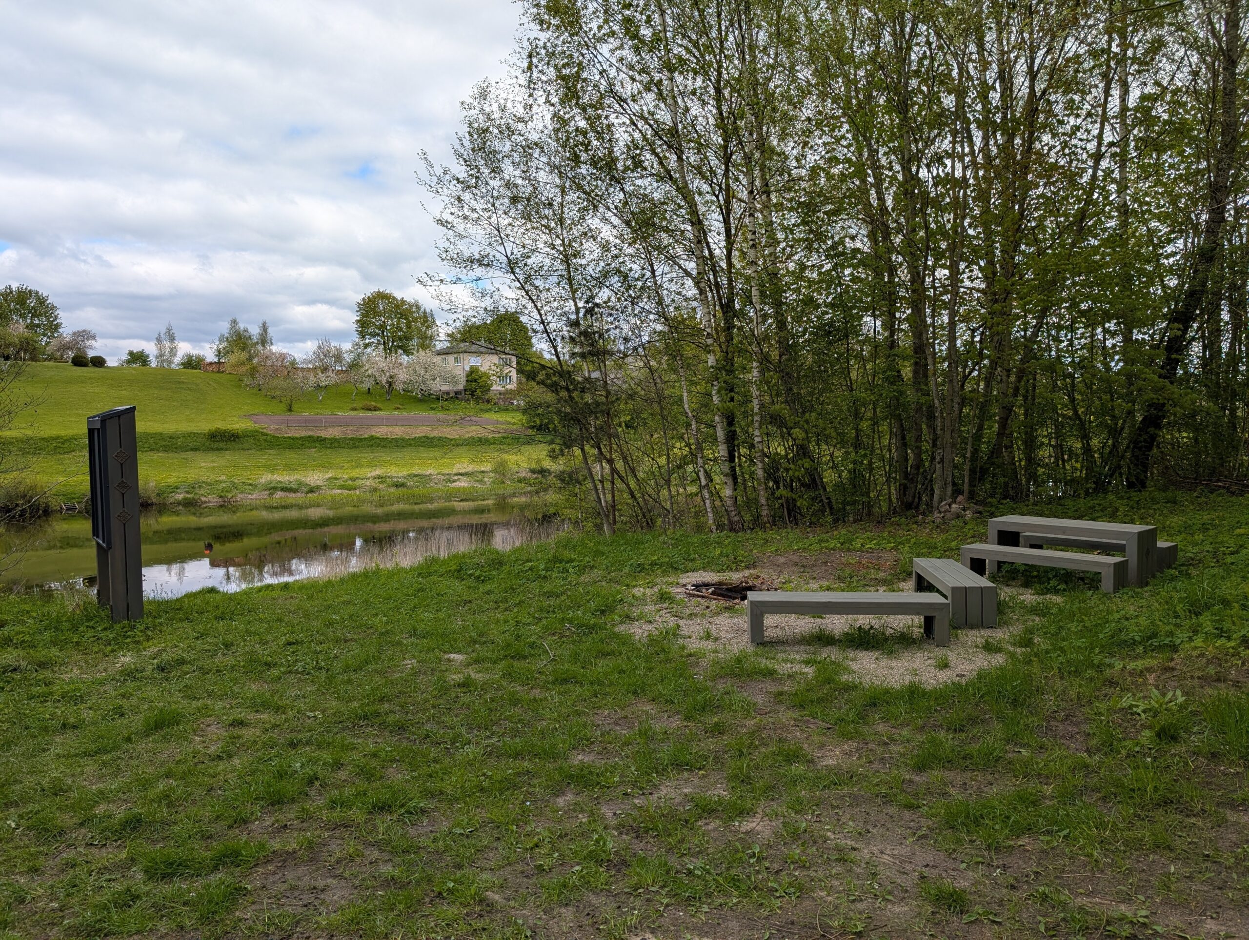 The photo of recreational place with benches near the river