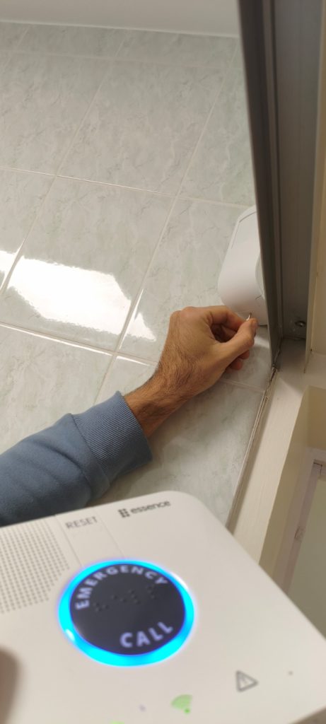 Person installing a door seal on tiled flooring, demonstrating home improvement techniques for better insulation and energy efficiency.