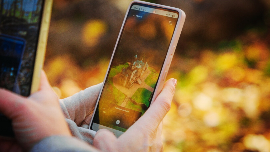 Person holding a smartphone displaying an augmented reality scene of a castle, surrounded by autumn leaves, highlighting the intersection of technology and nature. Person holding a smartphone displaying an augmented reality scene of a castle, surrounded by autumn leaves, highlighting the intersection of technology and nature.