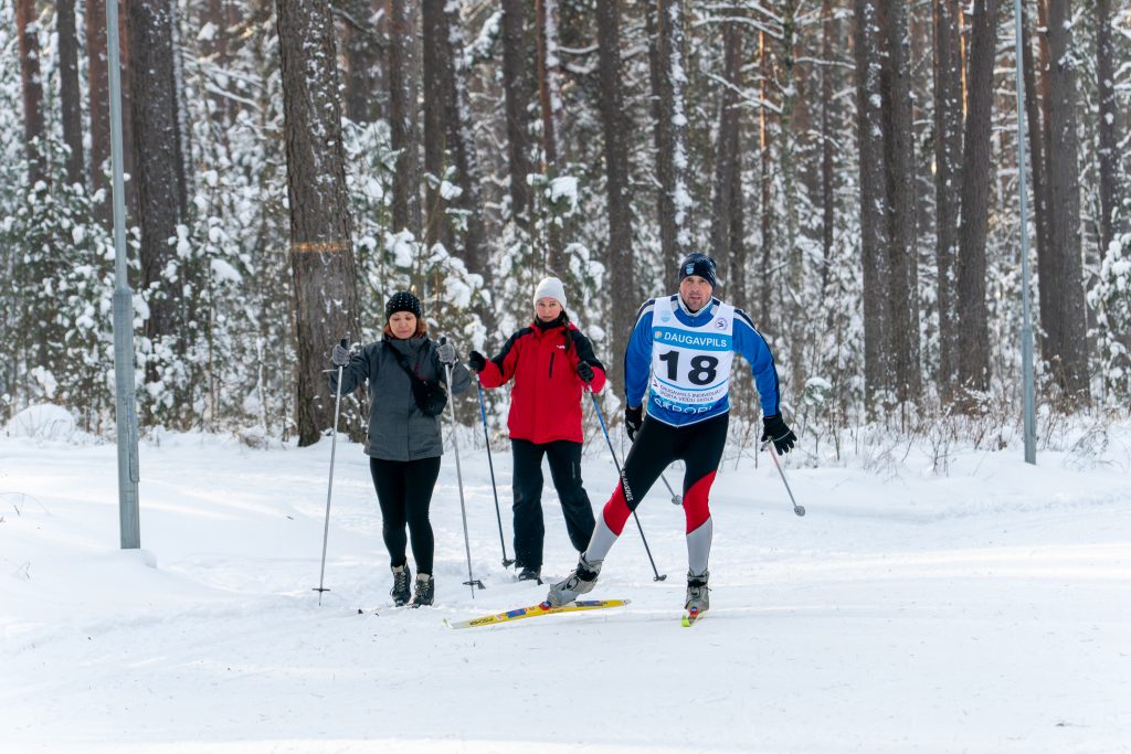 Three people on skis on the skiing track in forest actively skiing