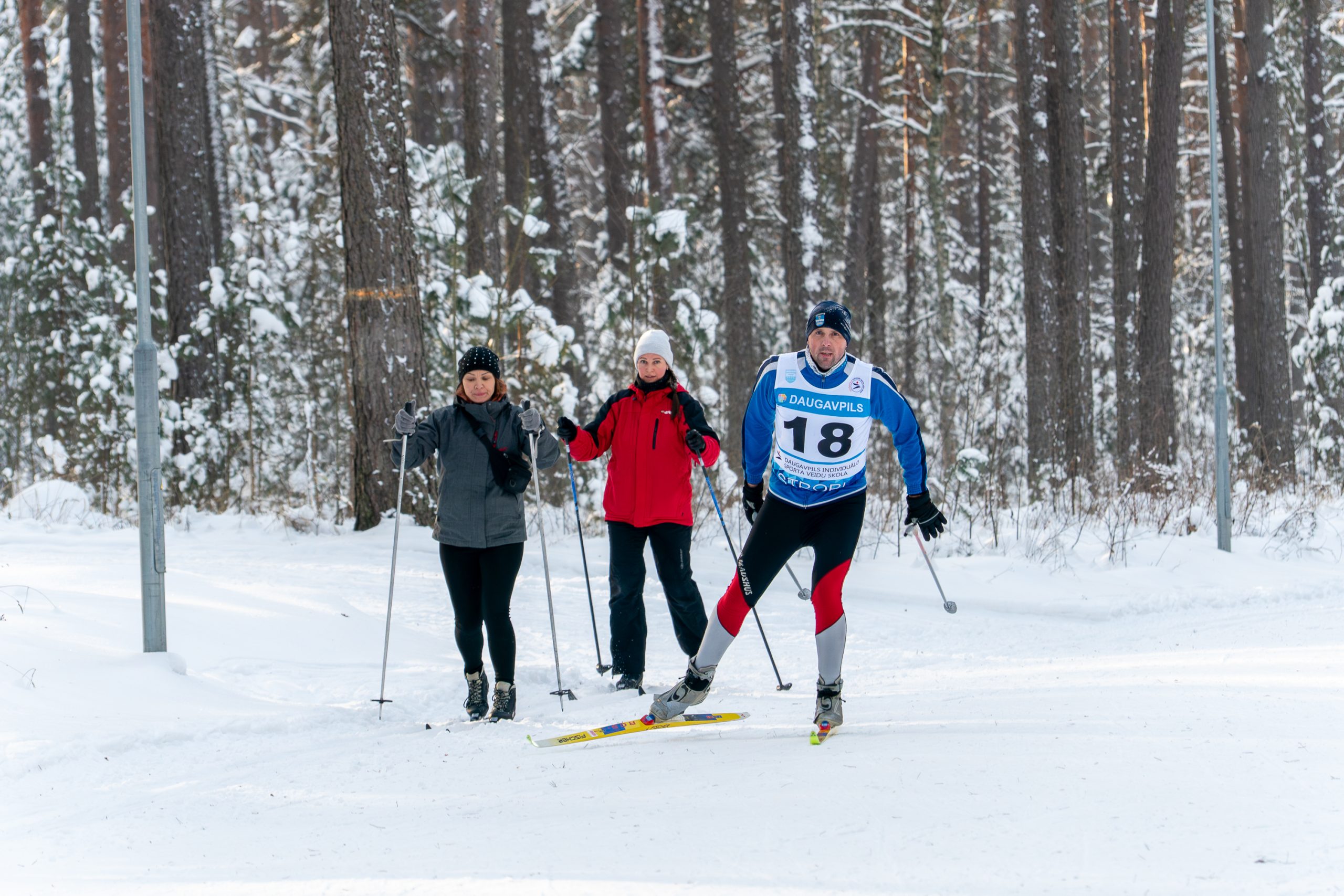 Three people on skis on the skiing track in forest actively skiing