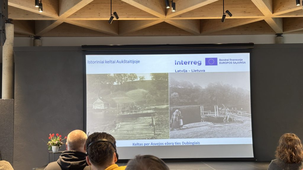 Image showing a presentation slide with a historical photograph on the left and a modern image on the right, depicting a rural landscape with a fence and people. The setting includes an audience in the foreground and a modern conference room design. Image showing a presentation slide with a historical photograph on the left and a modern image on the right, depicting a rural landscape with a fence and people. The setting includes an audience in the foreground and a modern conference room design.