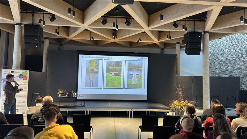Presentation in a modern auditorium featuring a large screen displaying three images, with an audience seated in front. The setting includes wooden ceiling beams and stage lighting, creating an engaging atmosphere for a seminar or workshop. Presentation in a modern auditorium featuring a large screen displaying three images, with an audience seated in front. The setting includes wooden ceiling beams and stage lighting, creating an engaging atmosphere for a seminar or workshop.