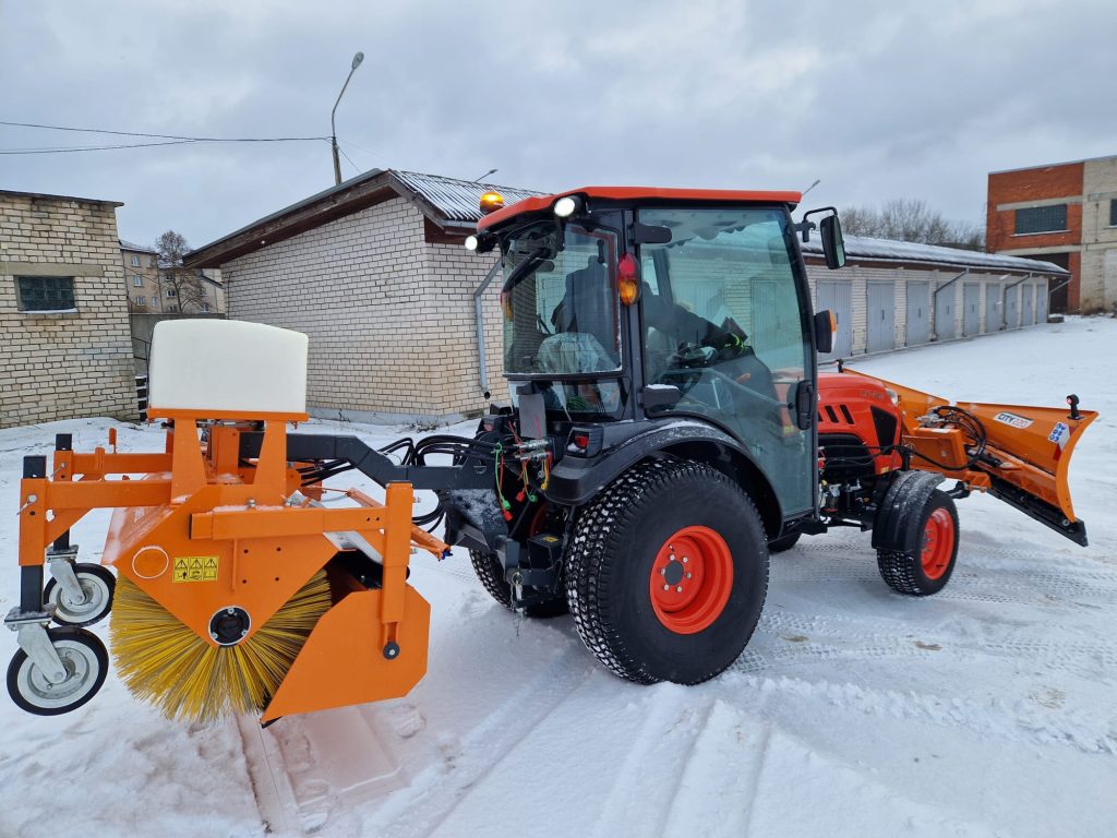 Compact tractor equipped with a snow plow attachment, clearing snow from a residential area with a cloudy sky in the background.