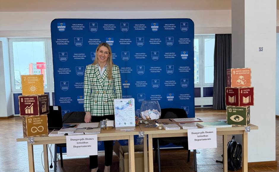 The woman posing on organisation's stand on Traid Fair event behind the tables with informative materials The woman posing on organisation's stand on Traid Fair event behind the tables with informative materials
