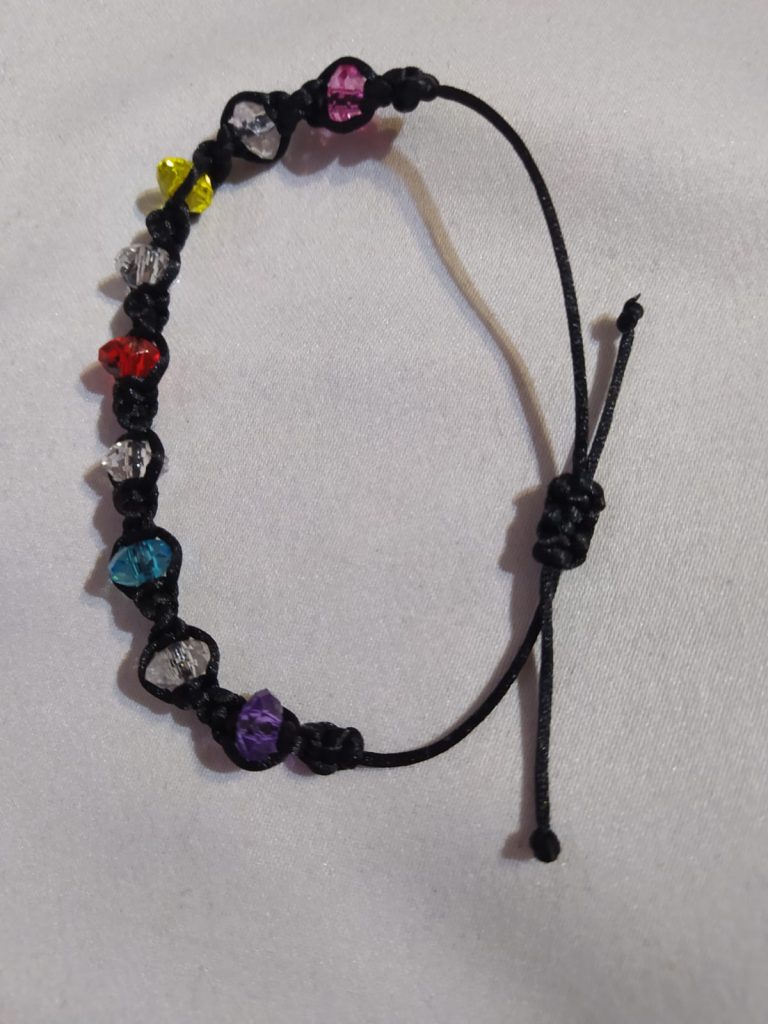 Colorful beaded bracelet on a black cord, featuring a variety of decorative beads in shades of red, blue, purple, and yellow, with an adjustable knot closure.