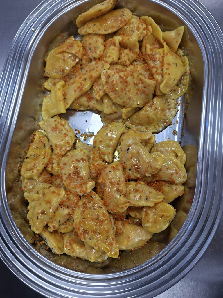 Plate of freshly made dumplings topped with orange fish roe, showcasing a delicious Asian-inspired dish in a stainless steel serving tray.