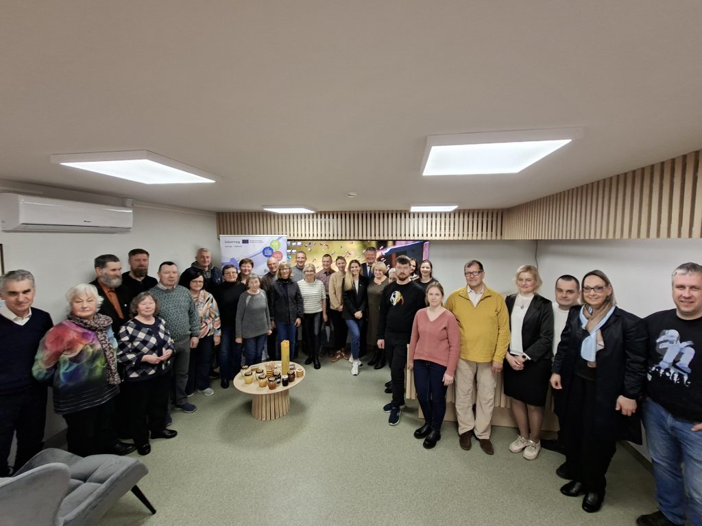 Group photo of diverse participants at a community event, showcasing collaboration and engagement in a modern meeting space. The setting includes a table with jars and candles, highlighting a warm and inviting atmosphere. Group photo of diverse participants at a community event, showcasing collaboration and engagement in a modern meeting space. The setting includes a table with jars and candles, highlighting a warm and inviting atmosphere.
