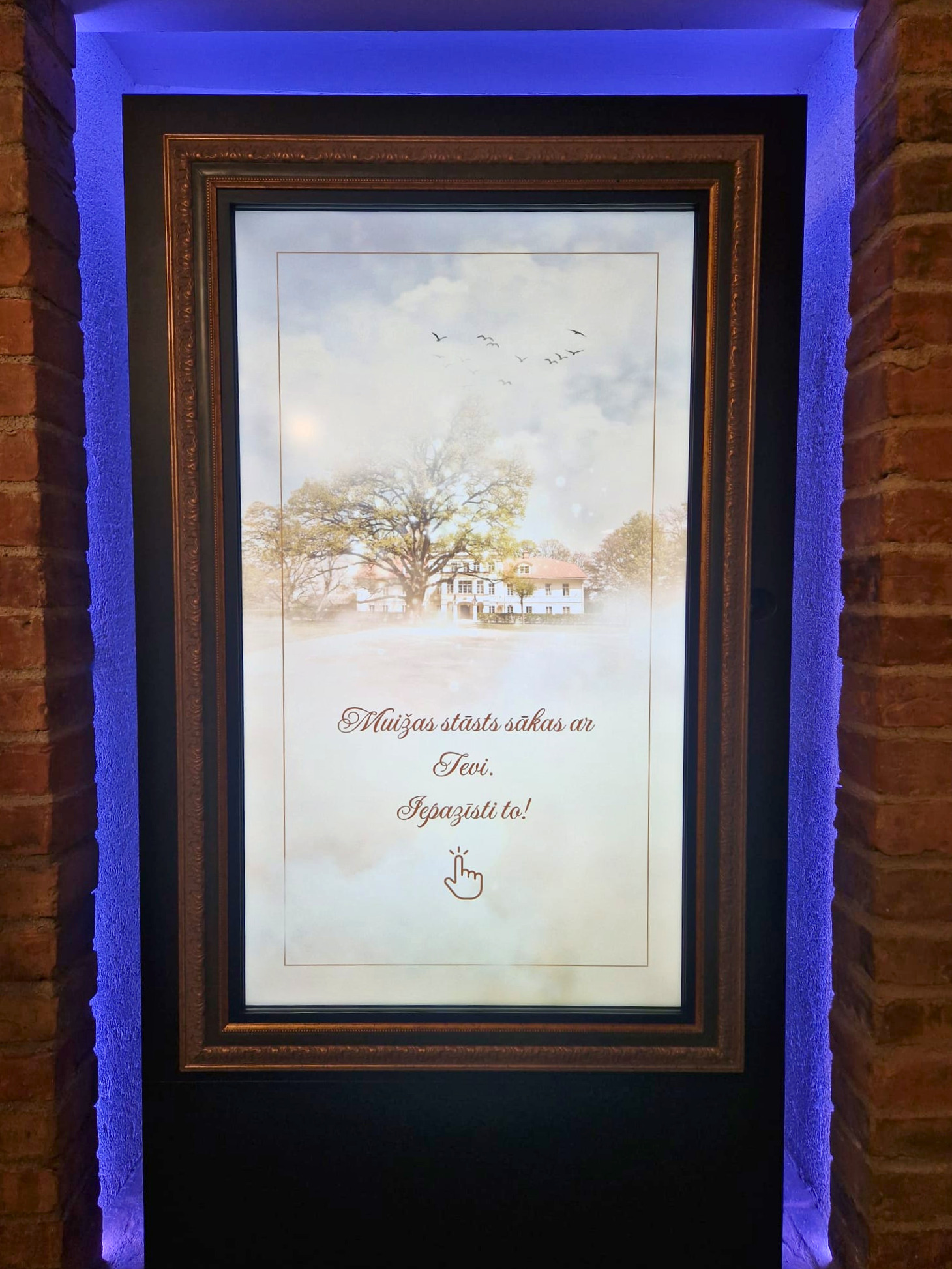 Digital display with a scenic background featuring a house and trees, framed elegantly. Text invites viewers to explore a story related to the location, enhancing visitor engagement. Ideal for tourism or historical sites.