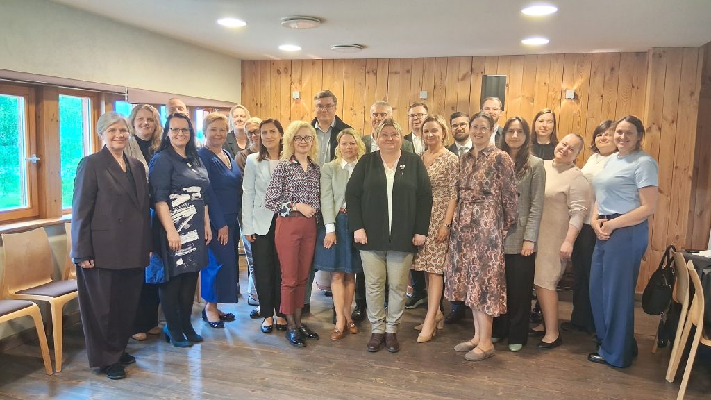 Group photo of diverse professionals gathered for a networking event, featuring individuals in business attire standing in a well-lit wooden interior. The setting highlights collaboration and engagement among attendees.