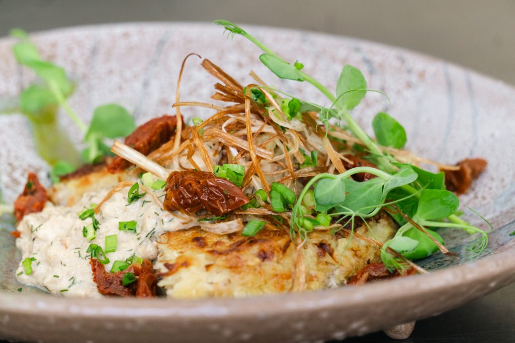 Delicious dish featuring creamy chicken topped with sun-dried tomatoes, crispy onions, and fresh microgreens, served on a rustic plate. Perfect for food enthusiasts seeking gourmet flavors.