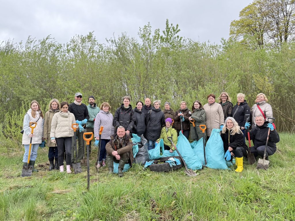 Group of volunteers participating in a community clean-up event, holding shovels and trash bags, surrounded by greenery. The event promotes environmental awareness and community involvement in local conservation efforts.