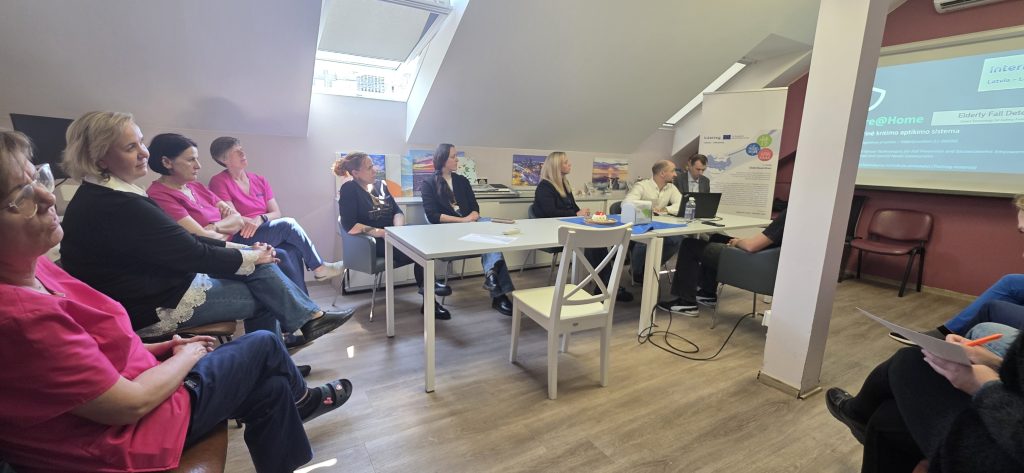 Image of a training session for the "ElderGuardian" project, featuring personnel in a meeting room. Attendees, including individuals in pink uniforms, are engaged in discussion while a presentation is displayed on a screen. The setting highlights the project's focus on training for elderly care technology implementation.