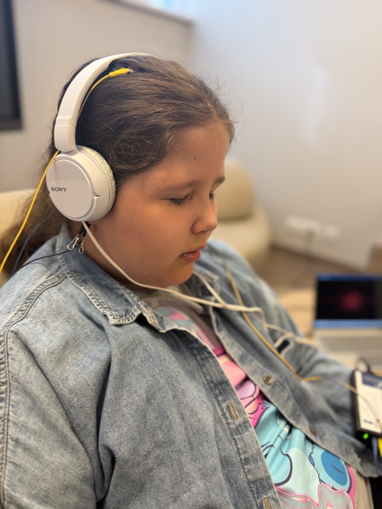 Child wearing Sony headphones, engaged in a digital rehabilitation session as part of the SPEED UP Project, highlighting the use of innovative technologies in therapy.