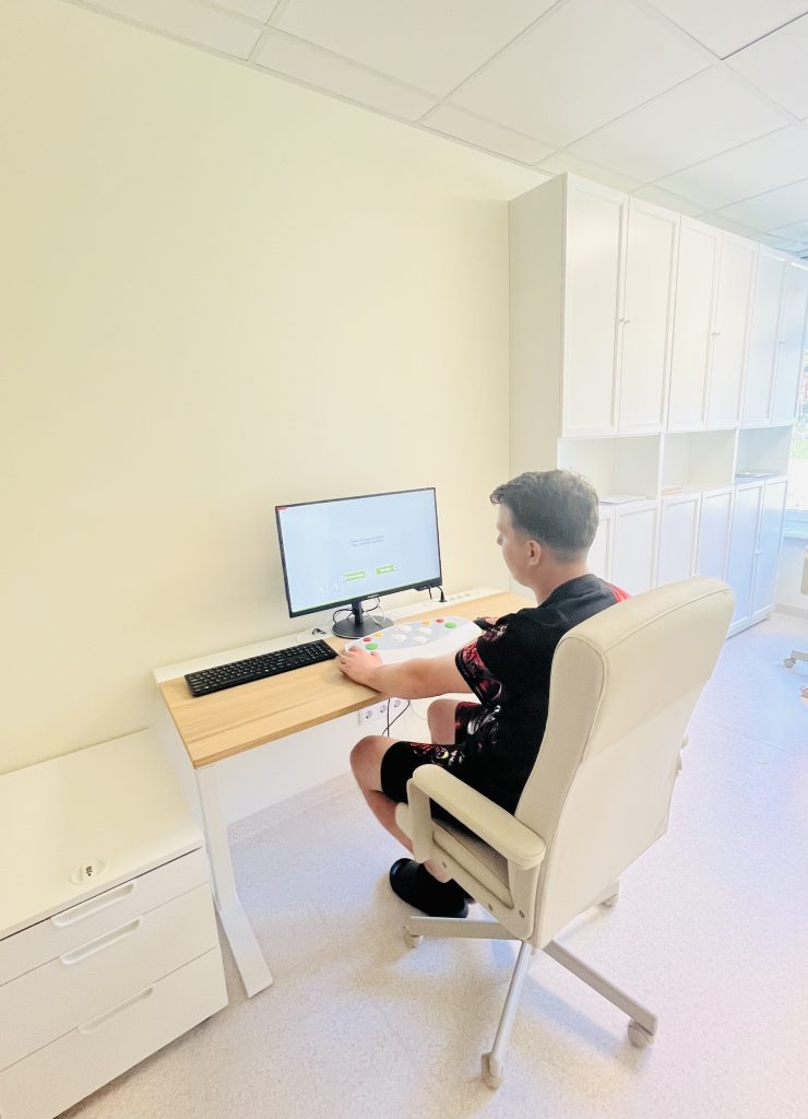 A young person using a computer with assistive technology in a modern rehabilitation office, showcasing innovative digital solutions for the SPEED UP project.