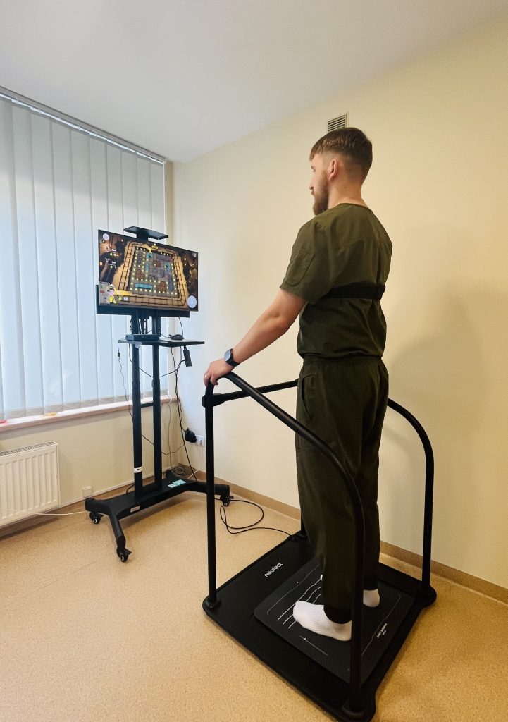 Individual participating in rehabilitation therapy using a motion-sensing platform connected to a monitor displaying interactive exercises as part of the SPEED UP Project, focused on innovative digital technologies in rehabilitation services.
