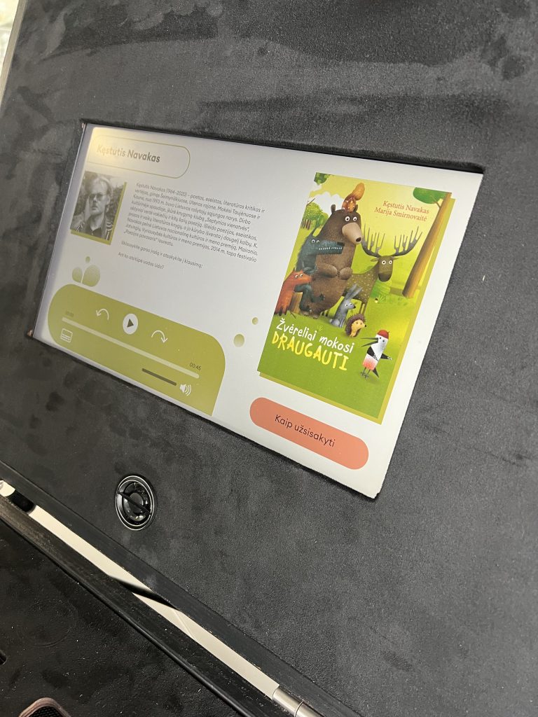 Interactive book suitcase featuring a touchscreen display showcasing the book "Žvėreliai mokosi draugauti" by Kęstutis Navakas and Marija Smirnovaitė, with audio playback and navigation options for an engaging literary experience. Interactive book suitcase featuring a touchscreen display showcasing the book "Žvėreliai mokosi draugauti" by Kęstutis Navakas and Marija Smirnovaitė, with audio playback and navigation options for an engaging literary experience.
