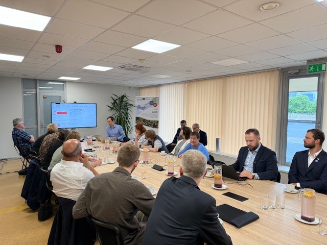 Meeting of stakeholders discussing the OASIS project in Latvia, focused on enhancing geospatial data quality and exploring new opportunities, with a presentation displayed on a screen and attendees seated at a conference table. Meeting of stakeholders discussing the OASIS project in Latvia, focused on enhancing geospatial data quality and exploring new opportunities, with a presentation displayed on a screen and attendees seated at a conference table.