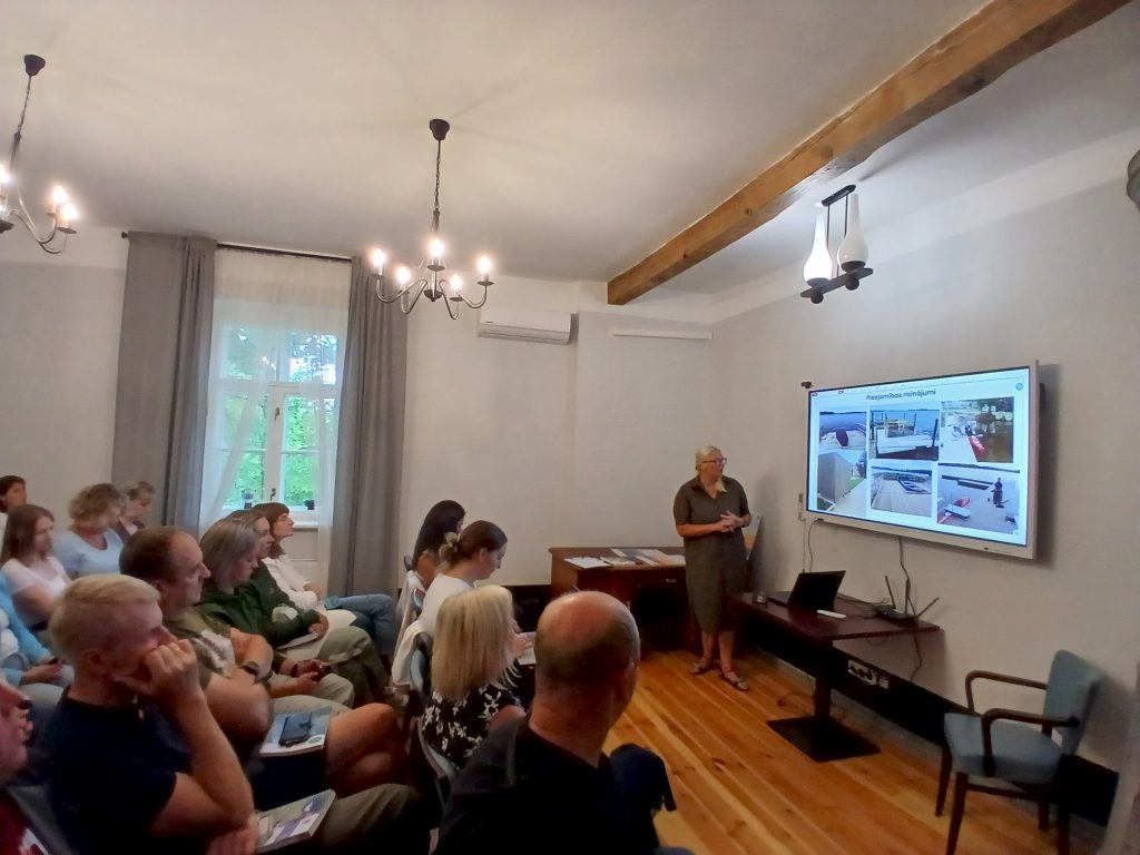 Speaker presenting water tourism trends at an industry seminar in Lielborne Manor, with an audience engaged in discussion. The presentation features images related to water tourism initiatives.