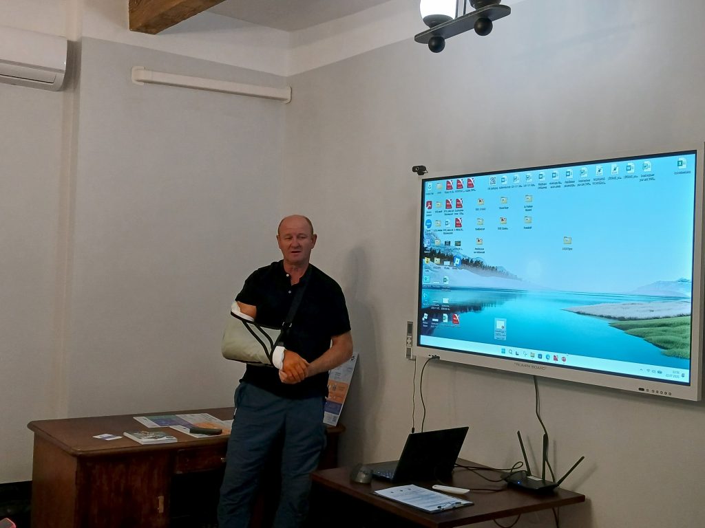 Speaker presenting at the water tourism seminar in Lielborne Manor, showcasing insights on industry trends, with a digital screen displaying relevant information.