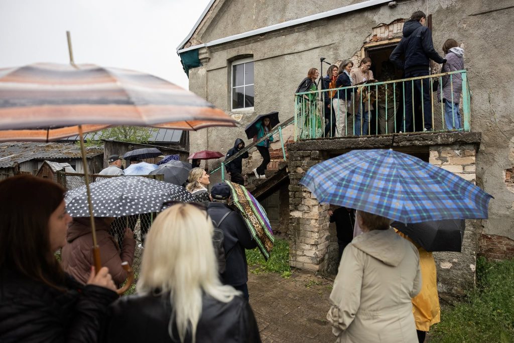 Visitors gather under umbrellas at the JEWEL Art Residency in Žagarė, as they prepare to enter the historic building despite rainy weather. Visitors gather under umbrellas at the JEWEL Art Residency in Žagarė, as they prepare to enter the historic building despite rainy weather.