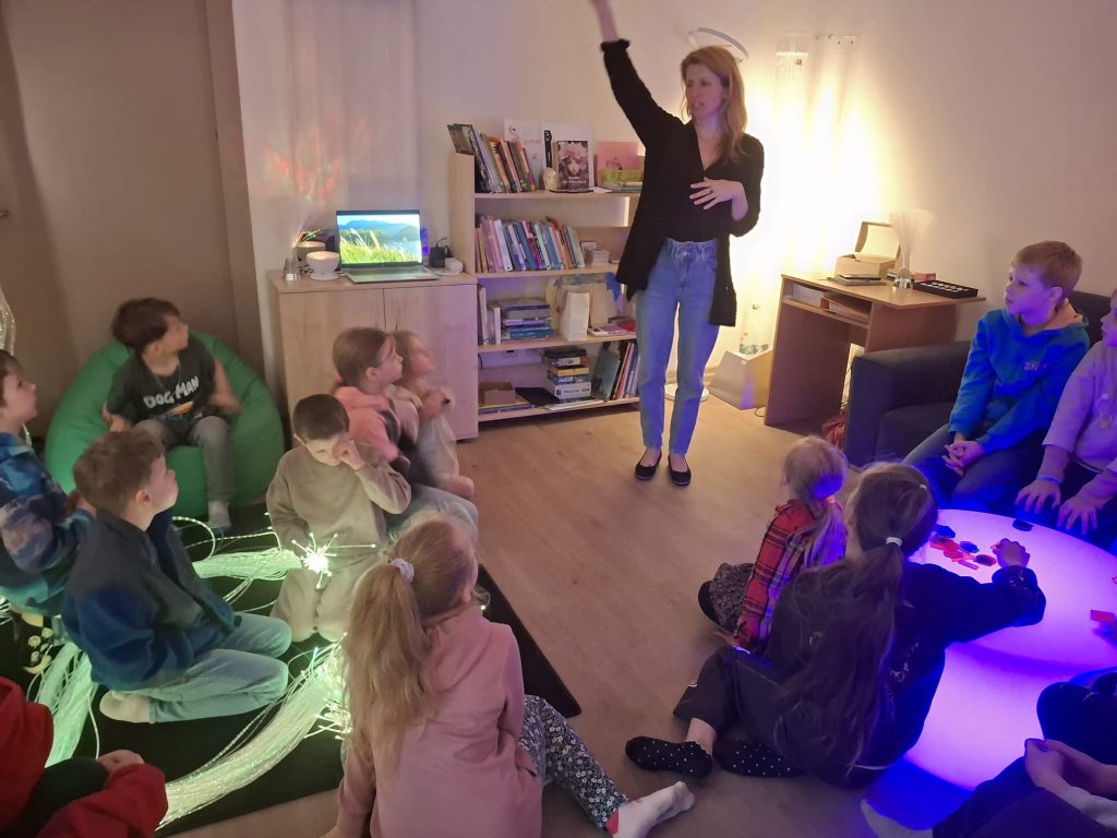 A facilitator engages a group of children in an interactive learning session, surrounded by colorful lighting and educational materials, as part of the INCLUSIVE project activities. A facilitator engages a group of children in an interactive learning session, surrounded by colorful lighting and educational materials, as part of the INCLUSIVE project activities.
