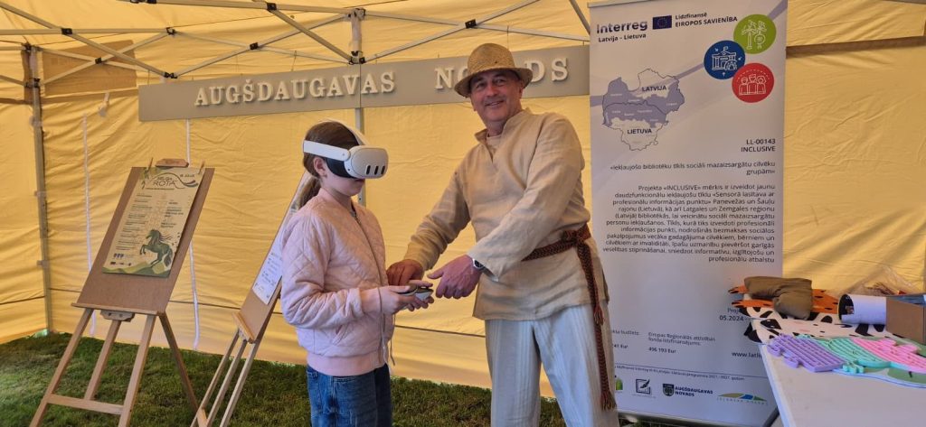 A child wearing a virtual reality headset interacts with an adult in traditional clothing at a project event in a tent, showcasing the INCLUSIVE initiative's focus on innovative technology and community engagement in Augšdaugava, Latvia. Informational materials are visible in the background, highlighting the project's goals and partnerships. A child wearing a virtual reality headset interacts with an adult in traditional clothing at a project event in a tent, showcasing the INCLUSIVE initiative's focus on innovative technology and community engagement in Augšdaugava, Latvia. Informational materials are visible in the background, highlighting the project's goals and partnerships.