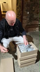 Man unpacking materials from a box in a museum setting, contributing to the MATOMI project focused on enhancing visitor experiences.