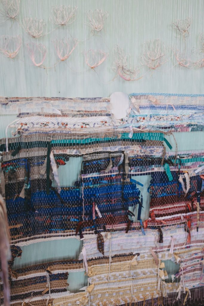 Textile artwork displayed at the JEWEL Art Residency in Žagarė, featuring intricate woven patterns and colorful fabric strips. The piece showcases a blend of textures and materials, highlighting the creative process and artistic expression involved in the residency. Textile artwork displayed at the JEWEL Art Residency in Žagarė, featuring intricate woven patterns and colorful fabric strips. The piece showcases a blend of textures and materials, highlighting the creative process and artistic expression involved in the residency.