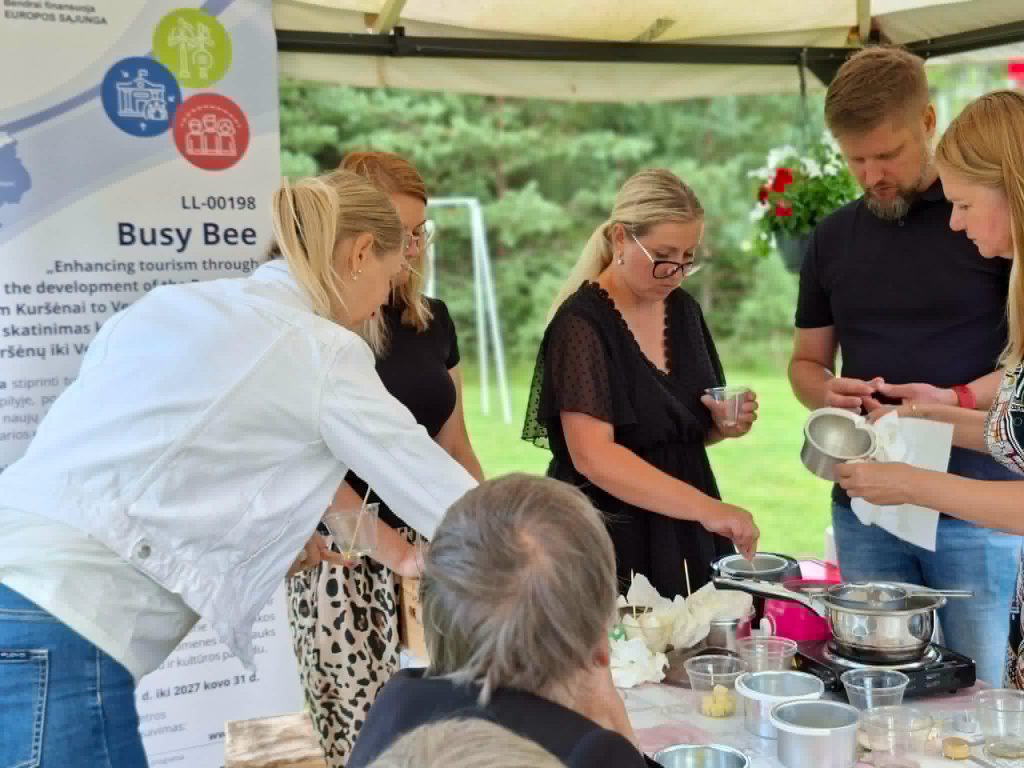 Participants engaged in an educational workshop on creating solid perfumes using scented wax, showcasing hands-on crafting techniques and collaboration in a natural outdoor setting.