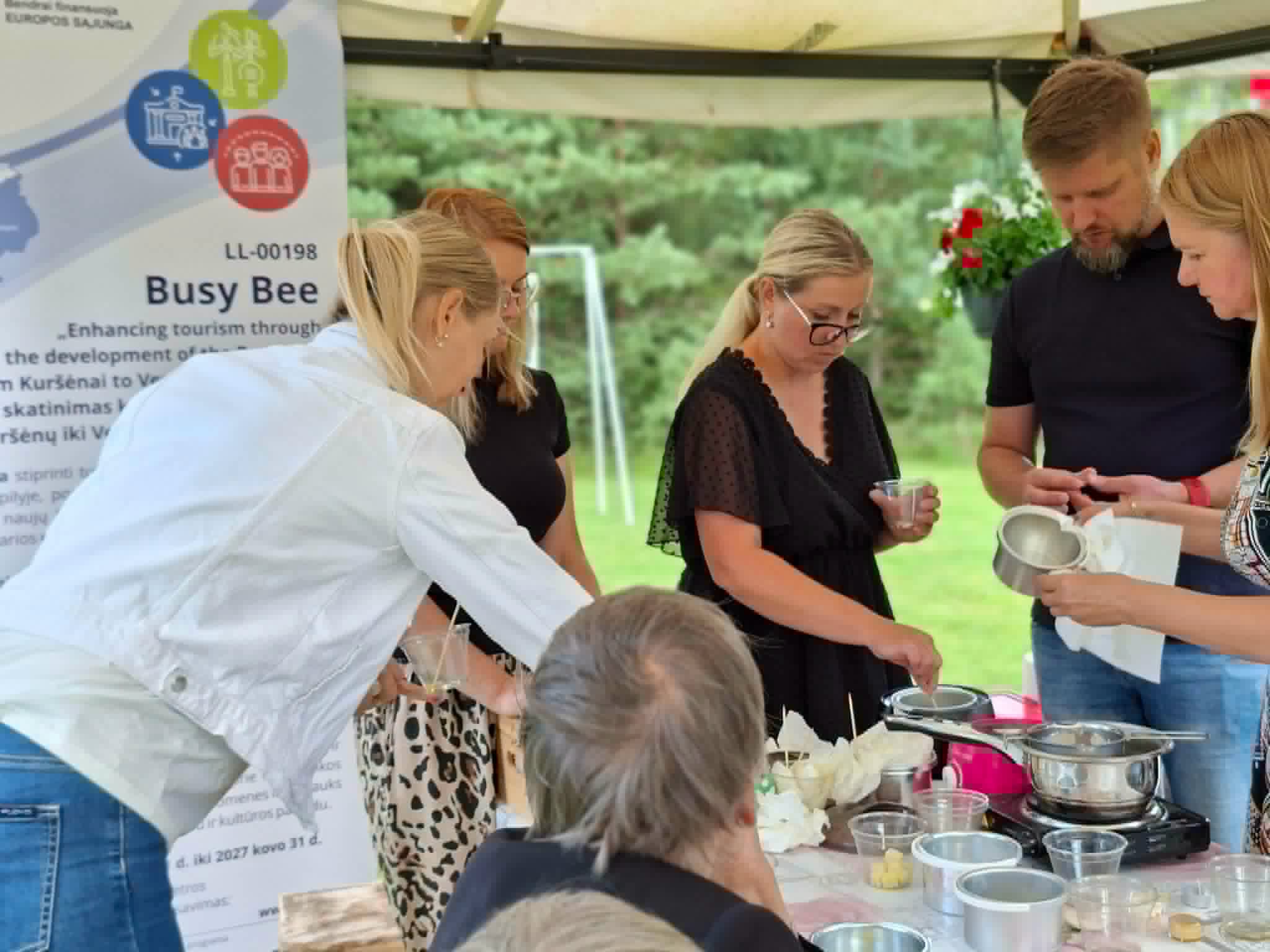 Participants engaged in an educational workshop on creating solid perfumes using scented wax, showcasing hands-on crafting techniques and collaboration in a natural outdoor setting.