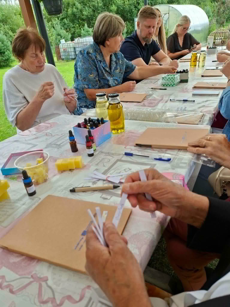 Participants engaged in an educational workshop on creating solid perfumes, surrounded by various fragrance oils, wax, and tools on a table.