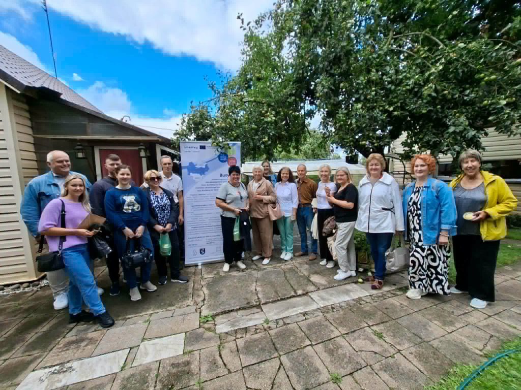 Group of participants gathered for the "Bee Therapy" educational workshop, standing in front of an informational banner in a lush outdoor setting, showcasing community engagement and interest in apitherapy.