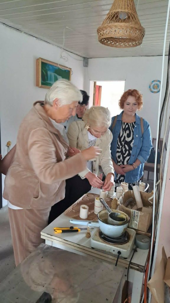 Participants engage in a hands-on activity during the "Bee Therapy" educational workshop, exploring bee-related products and techniques at a table filled with various materials and tools.