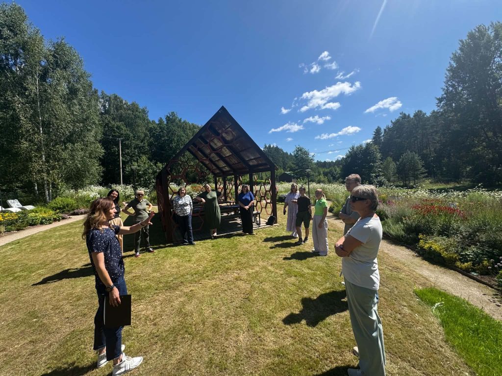 Group of educators engaged in a discussion outdoors at the Green Stories Project site, showcasing a unique educational experience amid a lush garden setting with a modern structure in the background. Group of educators engaged in a discussion outdoors at the Green Stories Project site, showcasing a unique educational experience amid a lush garden setting with a modern structure in the background.