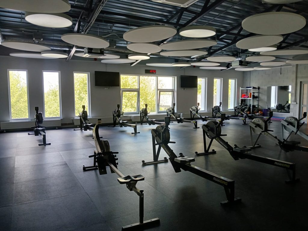 Modern fitness studio with rowing machines, large windows allowing natural light, and a spacious layout, designed for group workouts and training sessions in Jelgava. Modern fitness studio with rowing machines, large windows allowing natural light, and a spacious layout, designed for group workouts and training sessions in Jelgava.