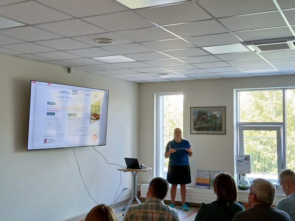 Speaker presenting at the seminar "Water Tourism Trends in Zemgale" in Jelgava, with a large screen displaying information on Latvia-Lithuania waterways, while attendees engage in the discussion. Speaker presenting at the seminar "Water Tourism Trends in Zemgale" in Jelgava, with a large screen displaying information on Latvia-Lithuania waterways, while attendees engage in the discussion.