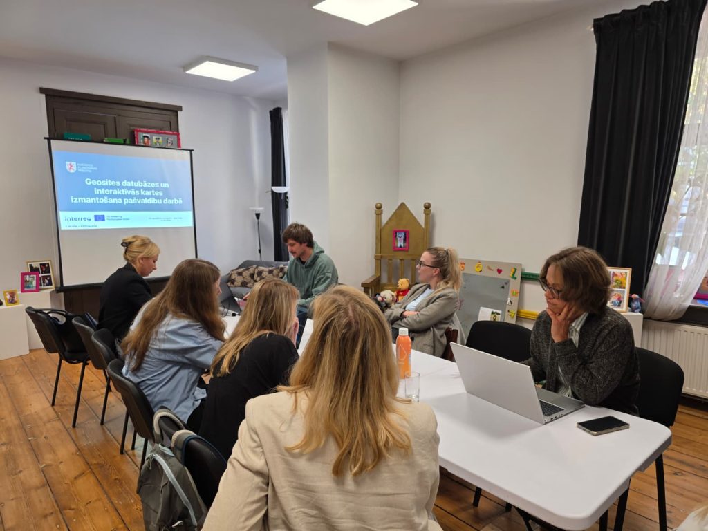 Participants engaged in a seminar in Saldus, discussing the Geosites database and its applications, with a presentation displayed in the background.