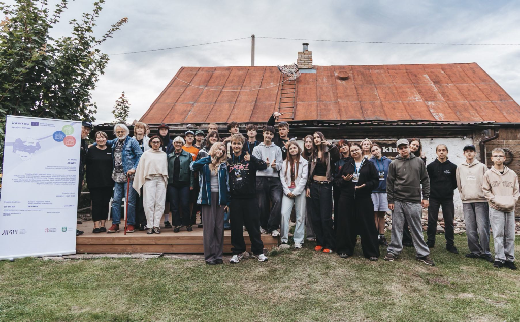 Group photo of young participants in the Action! Jewel-26 program, gathered outdoors in front of a rustic building, engaging in activities that explore Jewish heritage through filmmaking. The image showcases diverse youth smiling and posing, highlighting collaboration and cultural discovery.