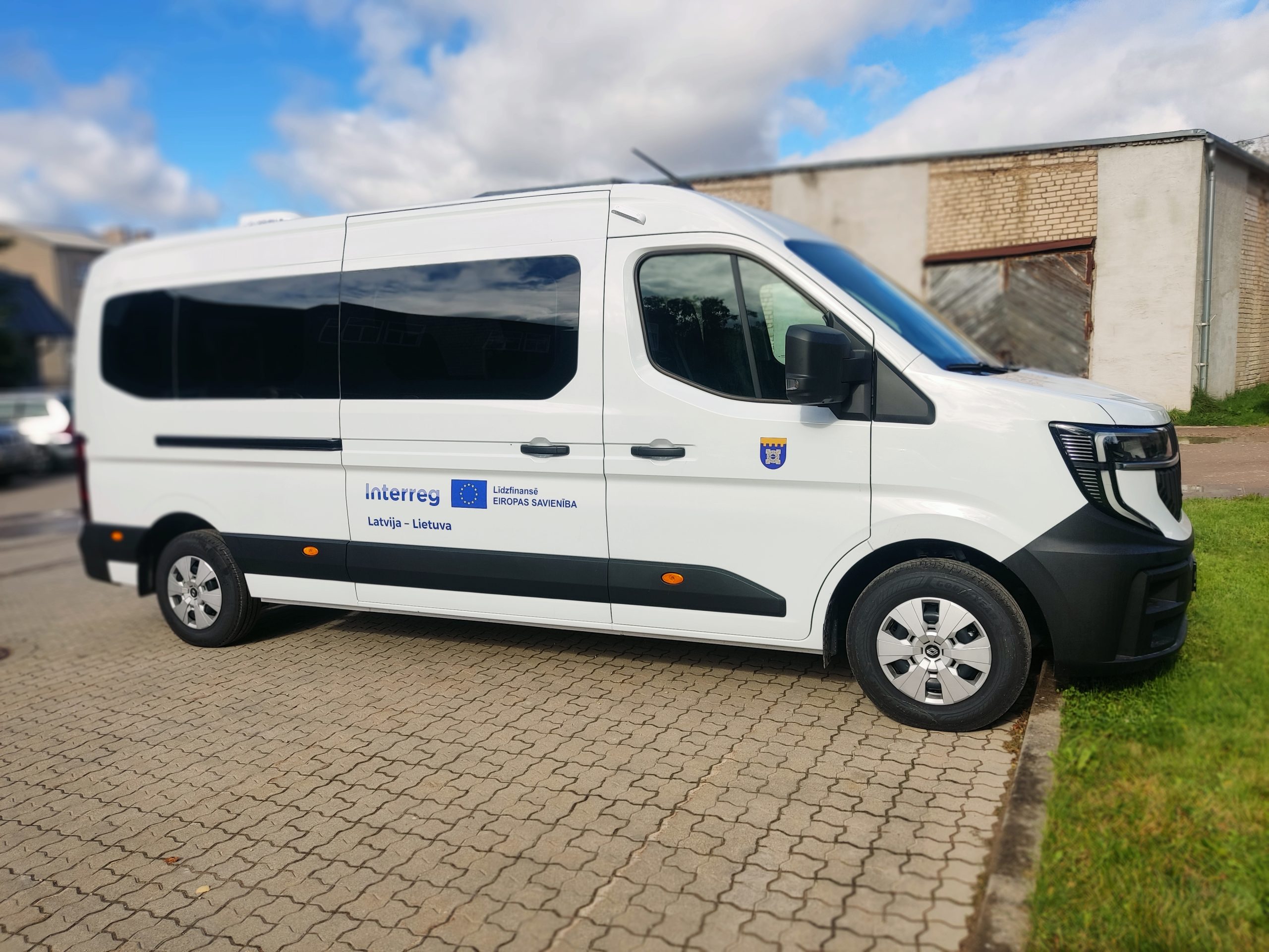 Specialized vehicle for the Social Service of Dobele County Municipality, featuring the Interreg logo, parked on a cobblestone surface with a clear blue sky in the background. Specialized vehicle for the Social Service of Dobele County Municipality, featuring the Interreg logo, parked on a cobblestone surface with a clear blue sky in the background.