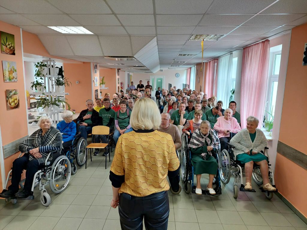 Group of elderly individuals in wheelchairs attending the SoCreative project meeting in Latvia, focusing on creativity and community engagement, with a speaker addressing the audience in a brightly lit room. Group of elderly individuals in wheelchairs attending the SoCreative project meeting in Latvia, focusing on creativity and community engagement, with a speaker addressing the audience in a brightly lit room.