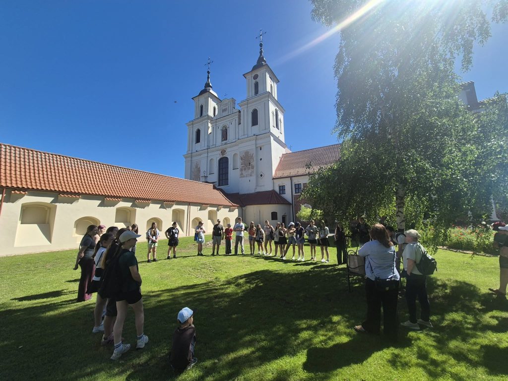 Group of people participating in a cultural event outdoors, with a historic church in the background under a clear blue sky, showcasing traditional culture and community engagement. Group of people participating in a cultural event outdoors, with a historic church in the background under a clear blue sky, showcasing traditional culture and community engagement.