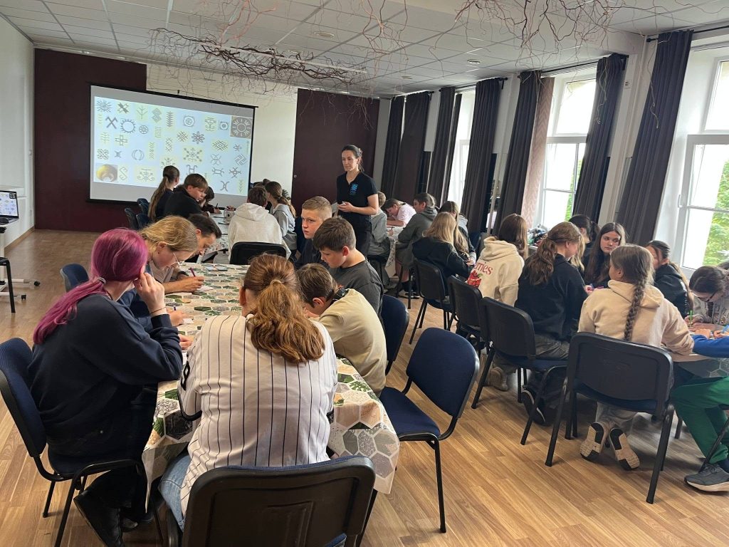 Group of young people engaging in a traditional cultural workshop, creating art inspired by historical symbols, with a presentation in the background, promoting hands-on learning and community involvement. Group of young people engaging in a traditional cultural workshop, creating art inspired by historical symbols, with a presentation in the background, promoting hands-on learning and community involvement.